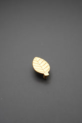 Tirador metálico dorado en forma de hoja sobre fondo gris