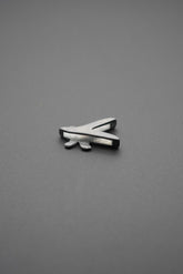 Vista en perspectiva del pin metálico con diseño de libélula en fondo gris