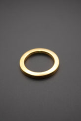 Arandela metálica circular dorada sobre fondo gris