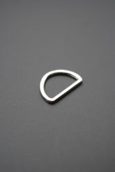 Arco metálico tipo D color plateado con acabado brillante sobre fondo gris