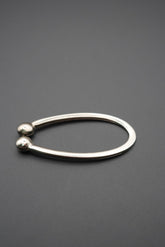 Anilla metálica ovalada con extremos esféricos sobre fondo gris