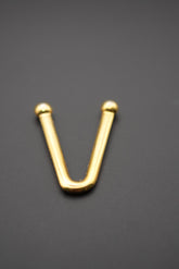 Gancho metálico en forma de V dorado colocado sobre superficie negra