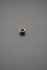 Cuenta metálica pulida sobre fondo gris, vista frontal