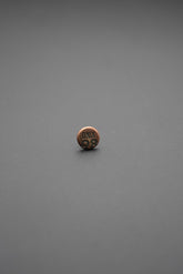 Remache metálico redondo con texto Onix 98 en acabado cobre envejecido sobre fondo gris