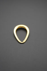 Argolla doble en forma de lágrima de latón con acabado dorado sobre fondo gris