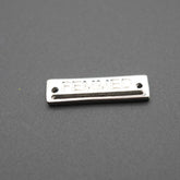 Placa metálica rectangular con grabado FEMMED sobre fondo gris