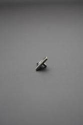 Remache metálico pequeño sobre fondo gris