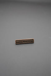 remache metálico rectangular cobre con texto Mostazza