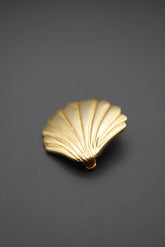 Broche con forma de concha dorada sobre fondo negro