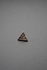 Botón metálico triangular sobre fondo gris