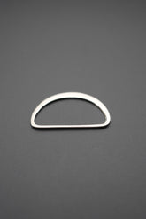 Argolla D plana metálica con acabado pulido vista frontal sobre fondo gris