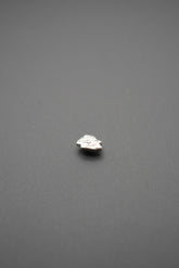 Botón de golpe metálico con diseño en relieve floral sobre fondo gris oscuro