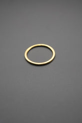 Anillo simple de metal con acabado dorado sobre superficie gris