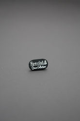 Remache ovalado negro con inscripción blanca special own collection sobre fondo gris