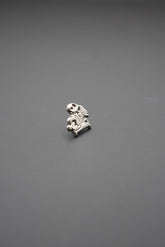 Pin metálico detalle frontal con diseño técnico en metal