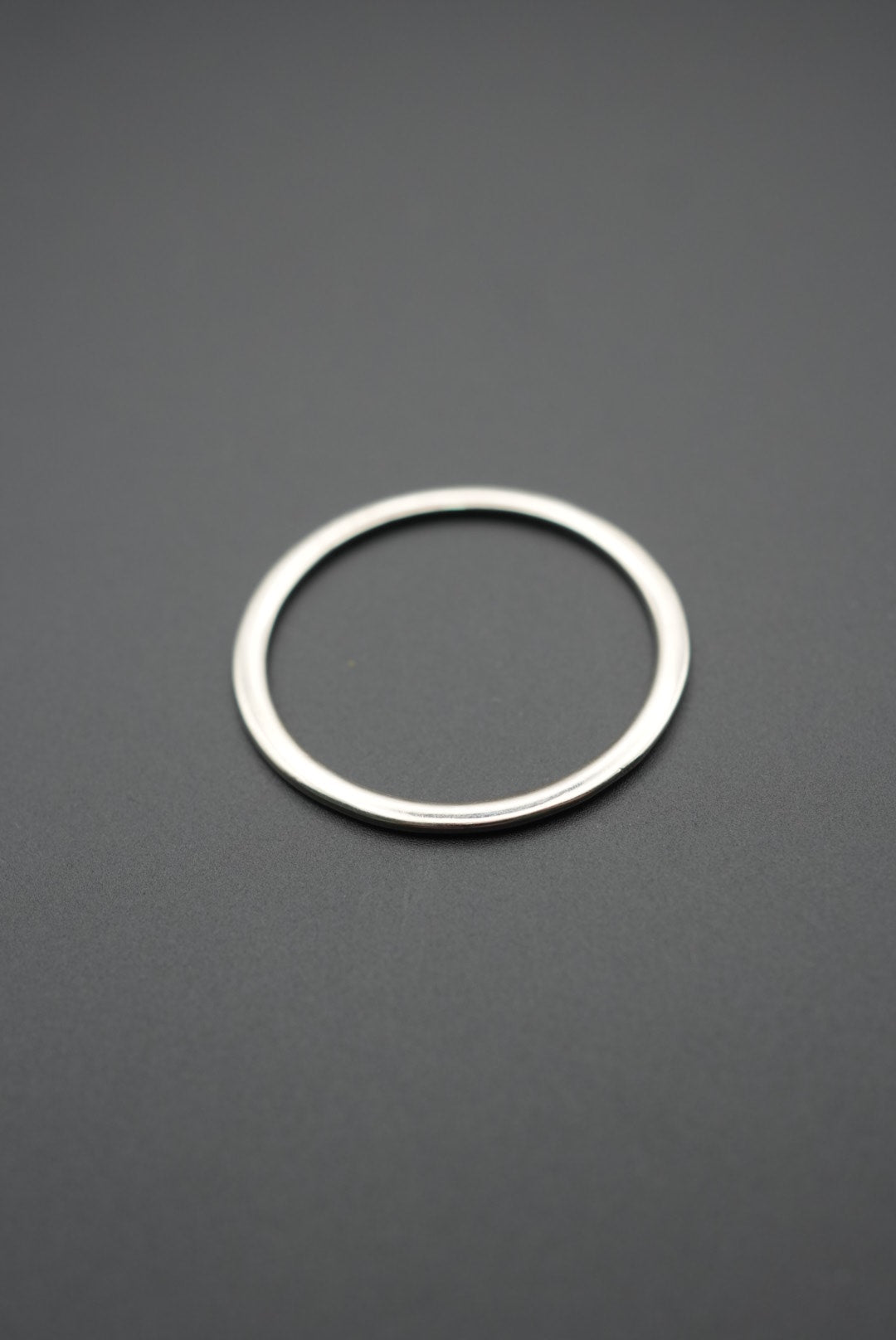 Anillo metálico redondo color plata sobre fondo gris