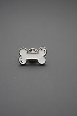 Pin metálico personalizado en forma de hueso blanco sobre fondo gris