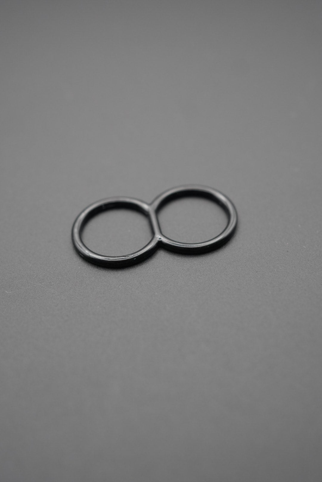 Anilla doble negra de metal sobre fondo gris