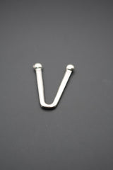 Gancho metálico en forma de V con extremos redondeados sobre fondo gris