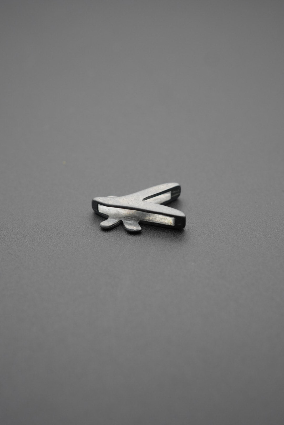 Vista en perspectiva del pin metálico con diseño de libélula en fondo gris