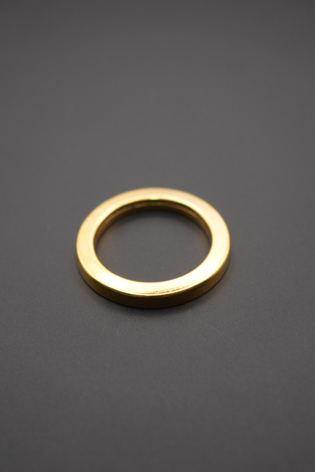 Arandela metálica circular dorada sobre fondo gris