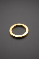 Arandela metálica circular dorada sobre fondo gris