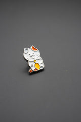Pin personalizado con diseño de gato Maneki-neko en colores blanco, naranja y amarillo sobre fondo gris