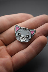 Pin personalizado con cara de gato color gris y rosa en mano