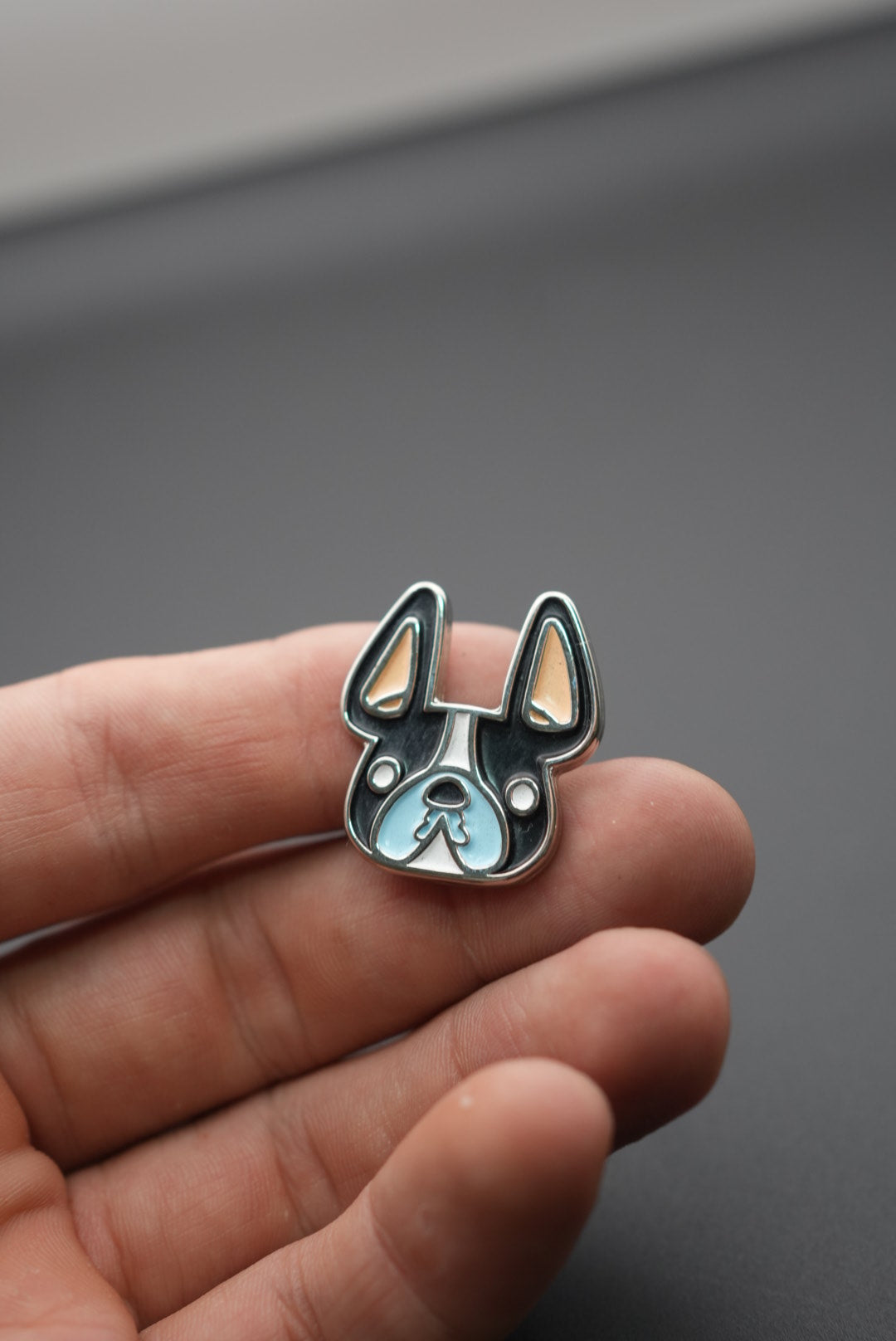 Pin personalizado con diseño de bulldog francés en mano masculina sobre fondo gris