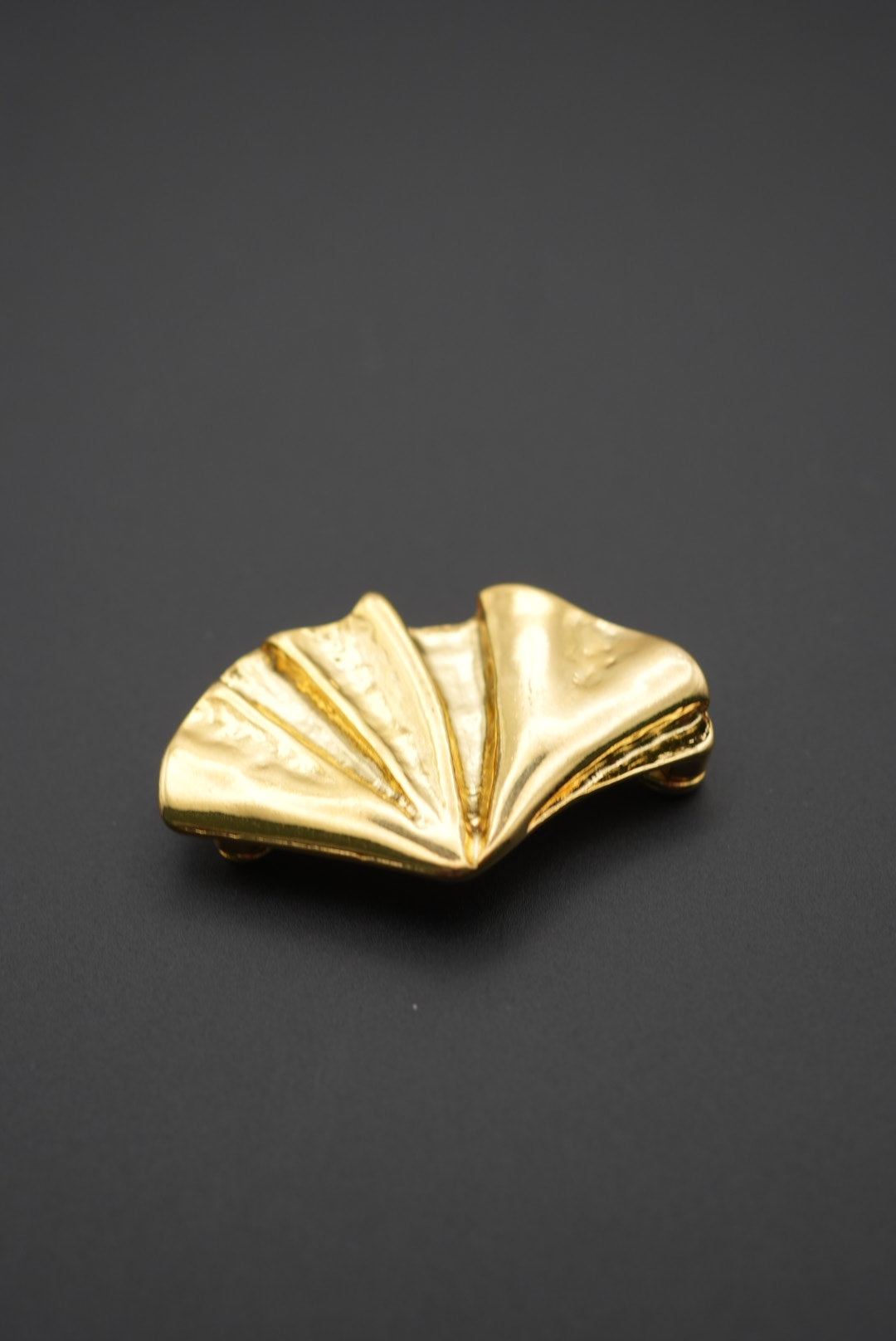 Vista frontal del broche con forma de concha con acabado dorado