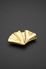 Vista frontal del broche con forma de concha con acabado dorado