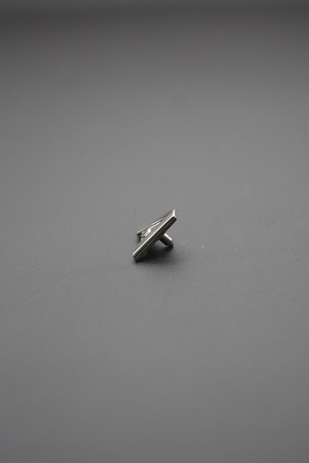 Remache metálico pequeño sobre fondo gris