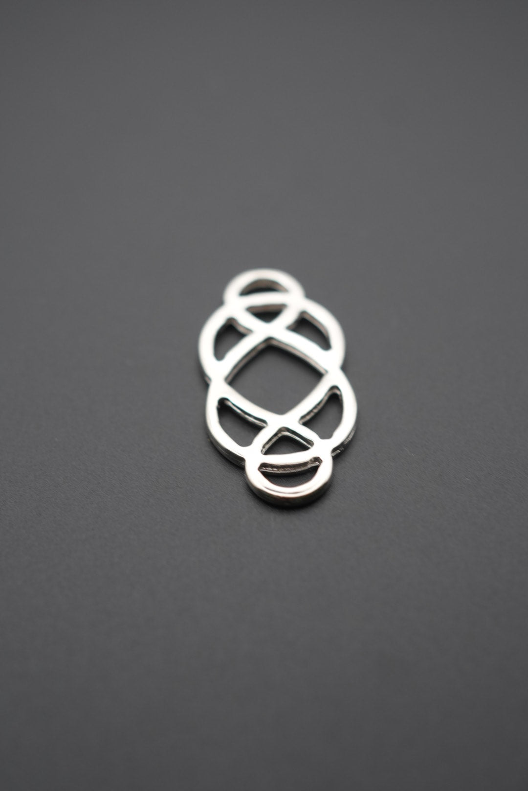 conector metálico de diseño geométrico sobre fondo gris