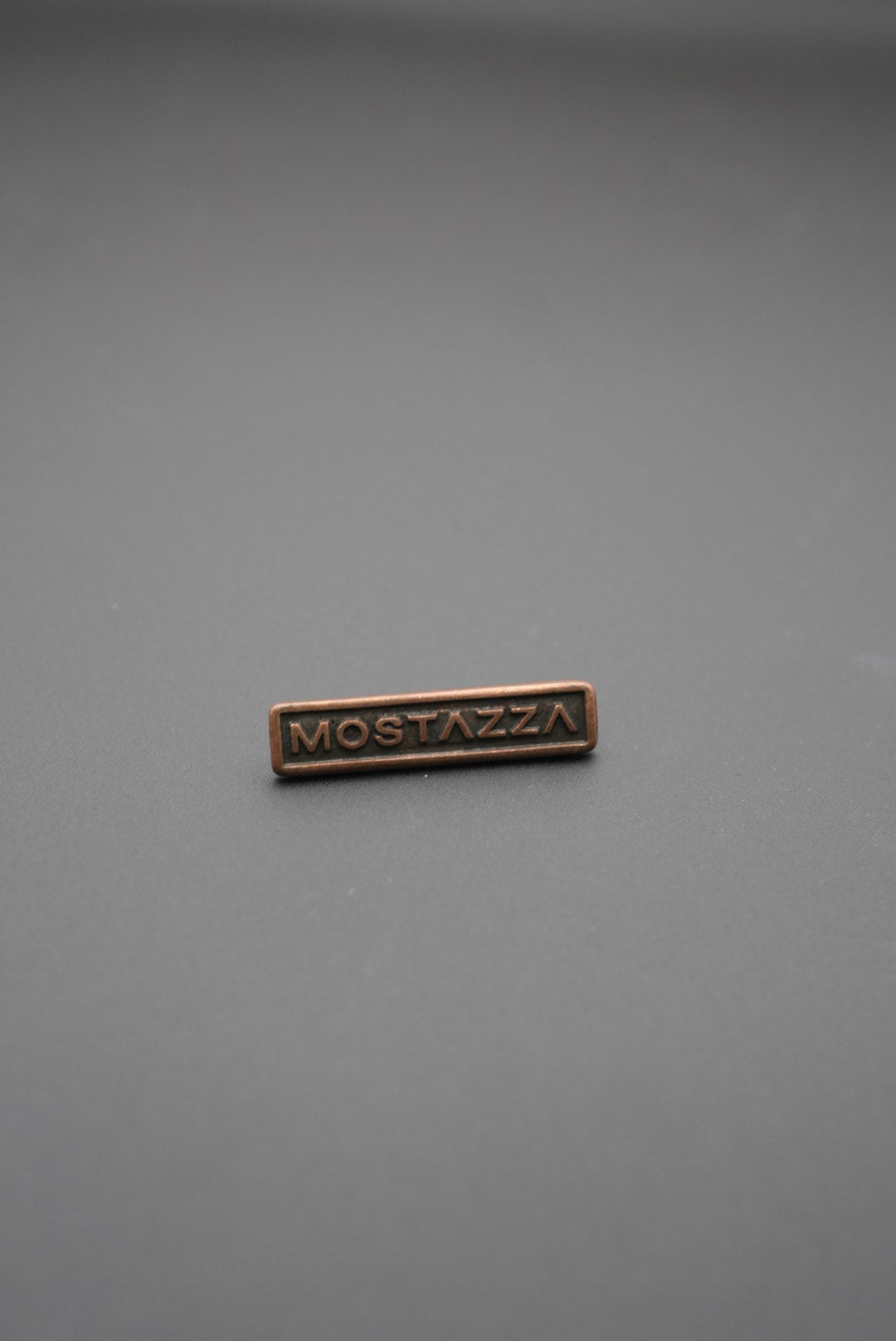 remache metálico rectangular cobre con texto Mostazza