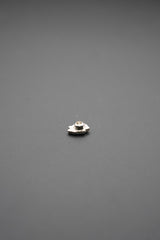 Pasador de metal pequeño con diseño floral en acabado plata sobre fondo gris