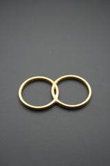 Anillo doble de latón pulido con acabado dorado sobre fondo gris oscuro