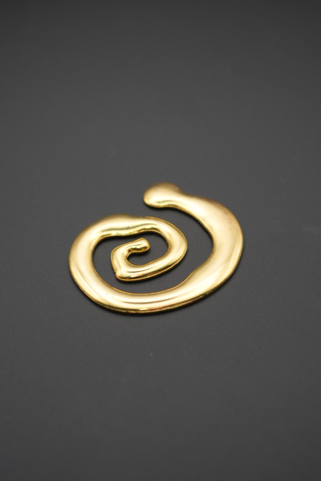 Broche dorado en forma de espiral sobre fondo gris oscuro