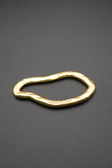 Pulsera dorada con forma orgánica y superficie pulida vista lateral