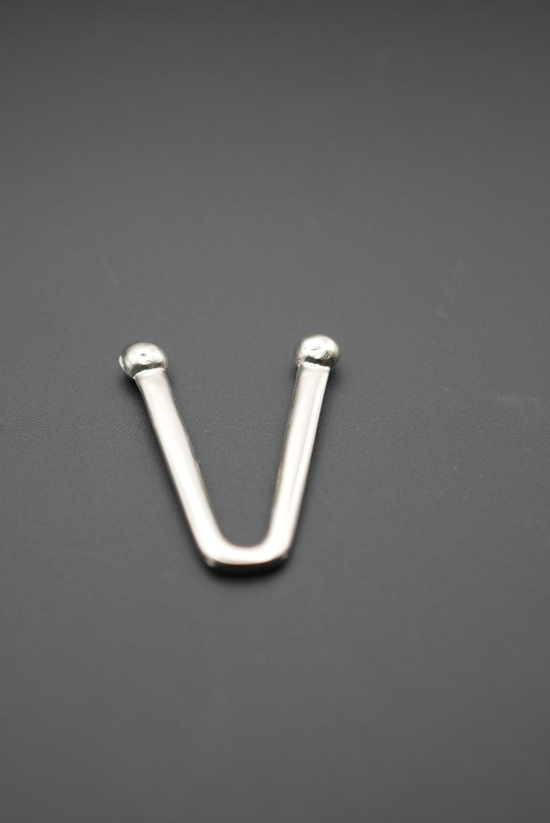 Vista frontal del gancho metálico en V mostrando su acabado pulido