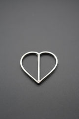 Hebilla en forma de corazón metal pulido sobre fondo gris