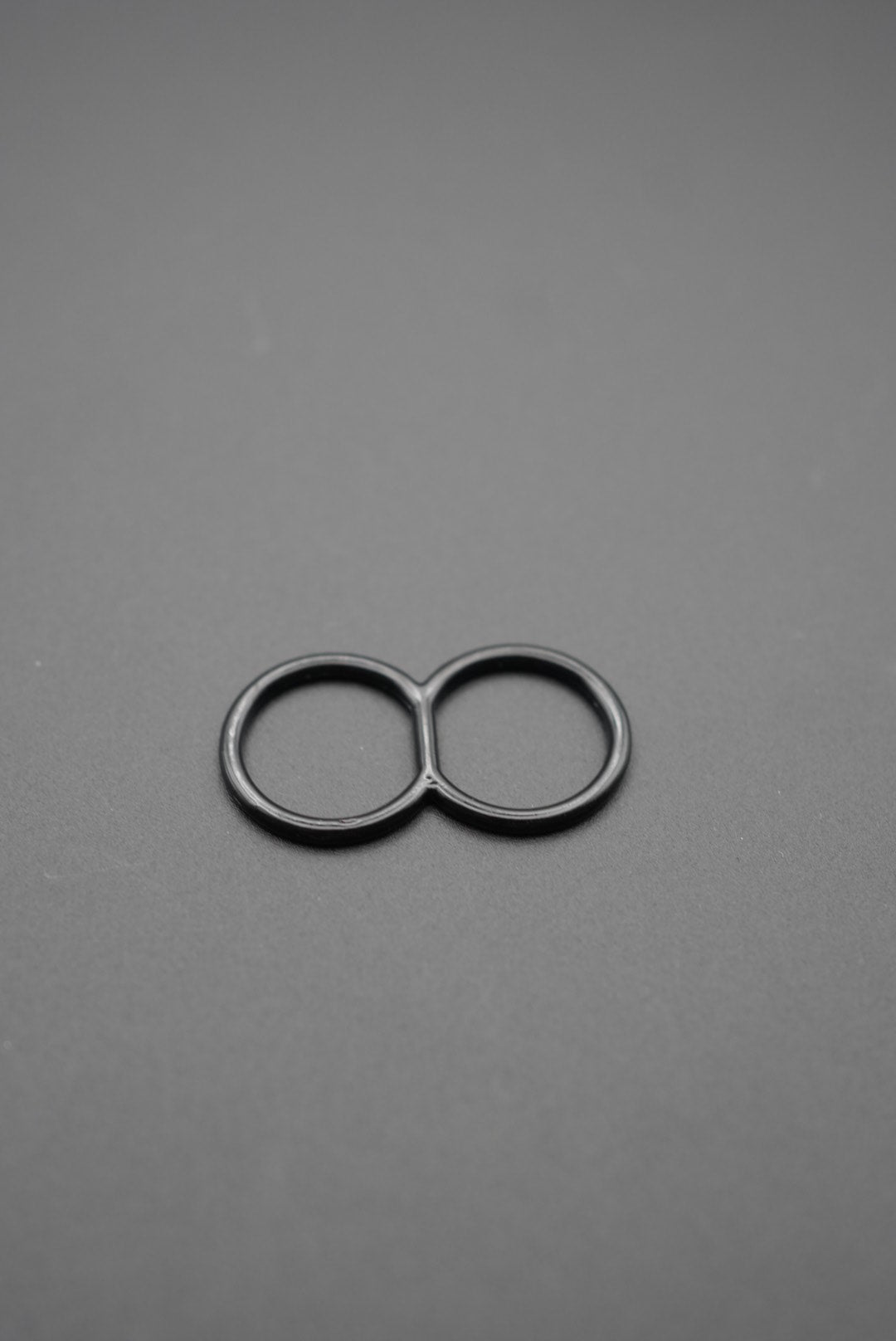 Primer plano de anilla metálica doble en color negro sobre superficie gris