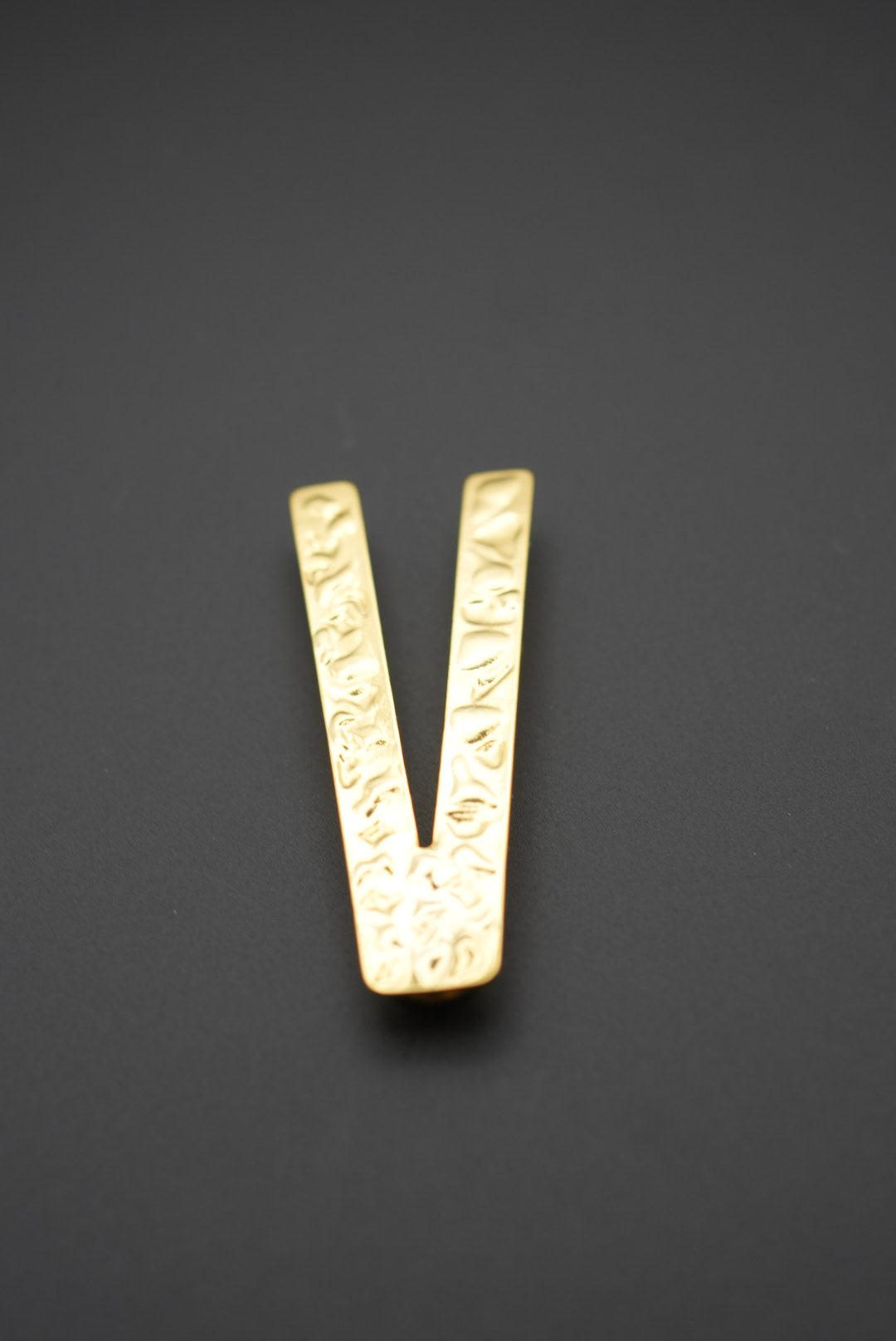 Pinza metálica dorada vista frontal mostrando textura en relieve