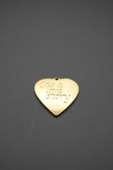 Detalle del colgante corazón dorado mostrando grabado 'It's a love story'