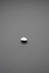 Detalle lateral del botón de golpe metálico con diseño floral en relieve