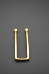 Detalle del pasador dorado rectangular sobre fondo gris oscuro