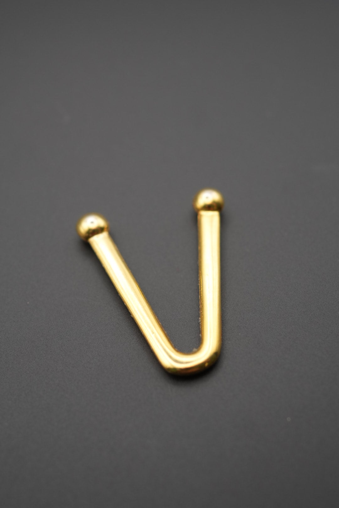 Vista de gancho metálico dorado en forma de V con fondo negro