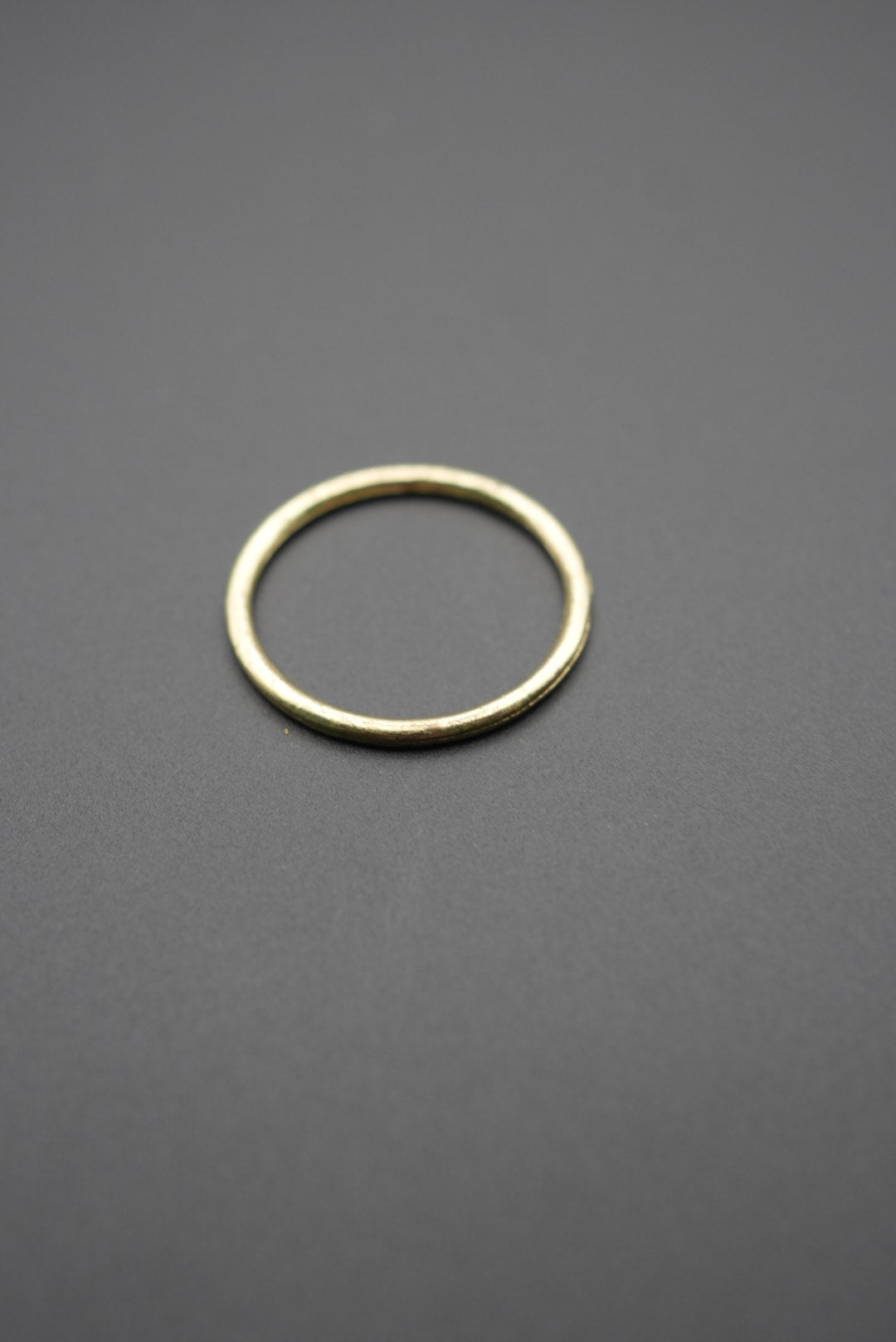 Anillo metálico redondo color dorado sobre fondo gris