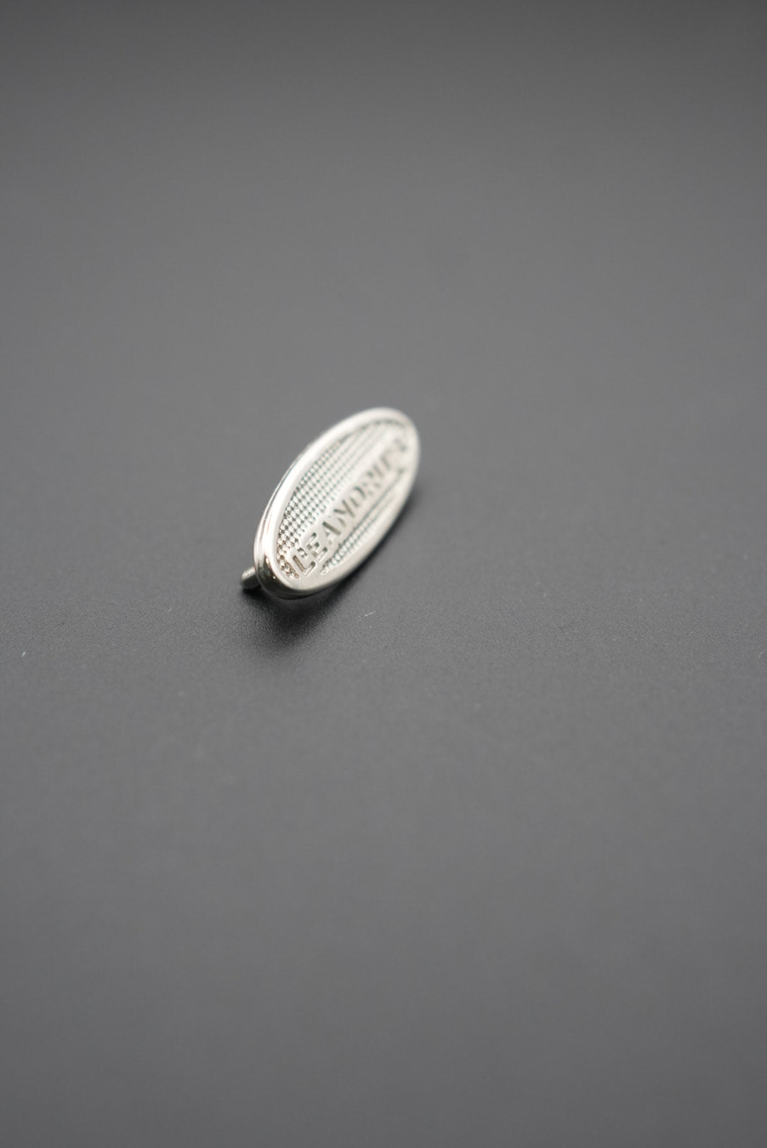 Vista lateral del remache ovalado metálico Leandrus mostrando relieve y textura