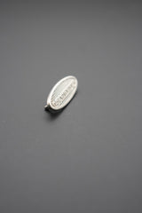 Vista lateral del remache ovalado metálico Leandrus mostrando relieve y textura