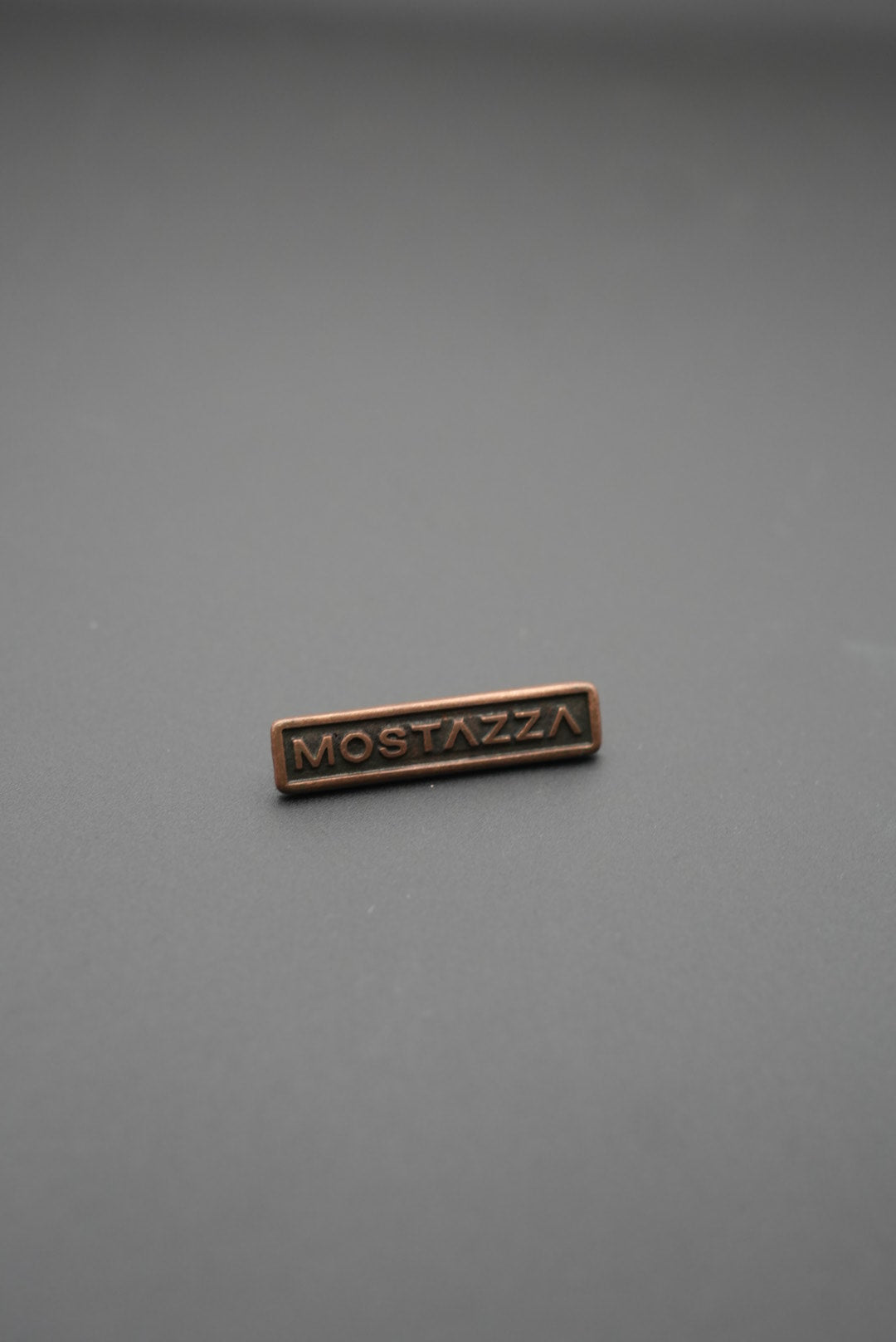 remache metálico cobre envejecido vista frontal con texto Mostazza